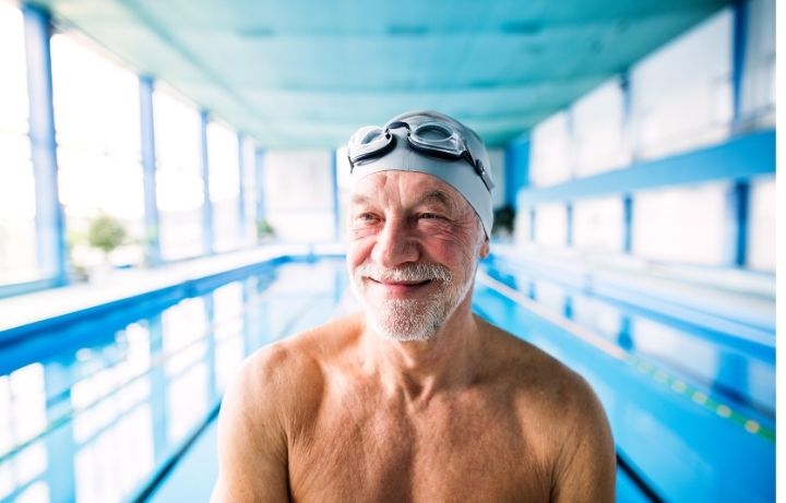 Vintage Fitness client over 55 smiling after swimming workout at indoor pool