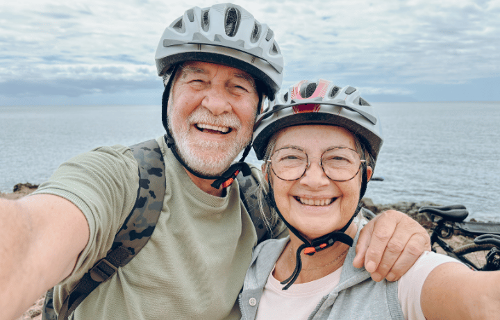 A happy couple over 60 keeping active by going for a bike ride, but even small movements everyday make a big difference in preventing age related muscles loss.